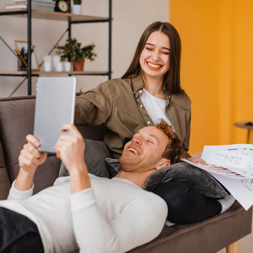 Smiling couple on a sofa making plans together with a tablet