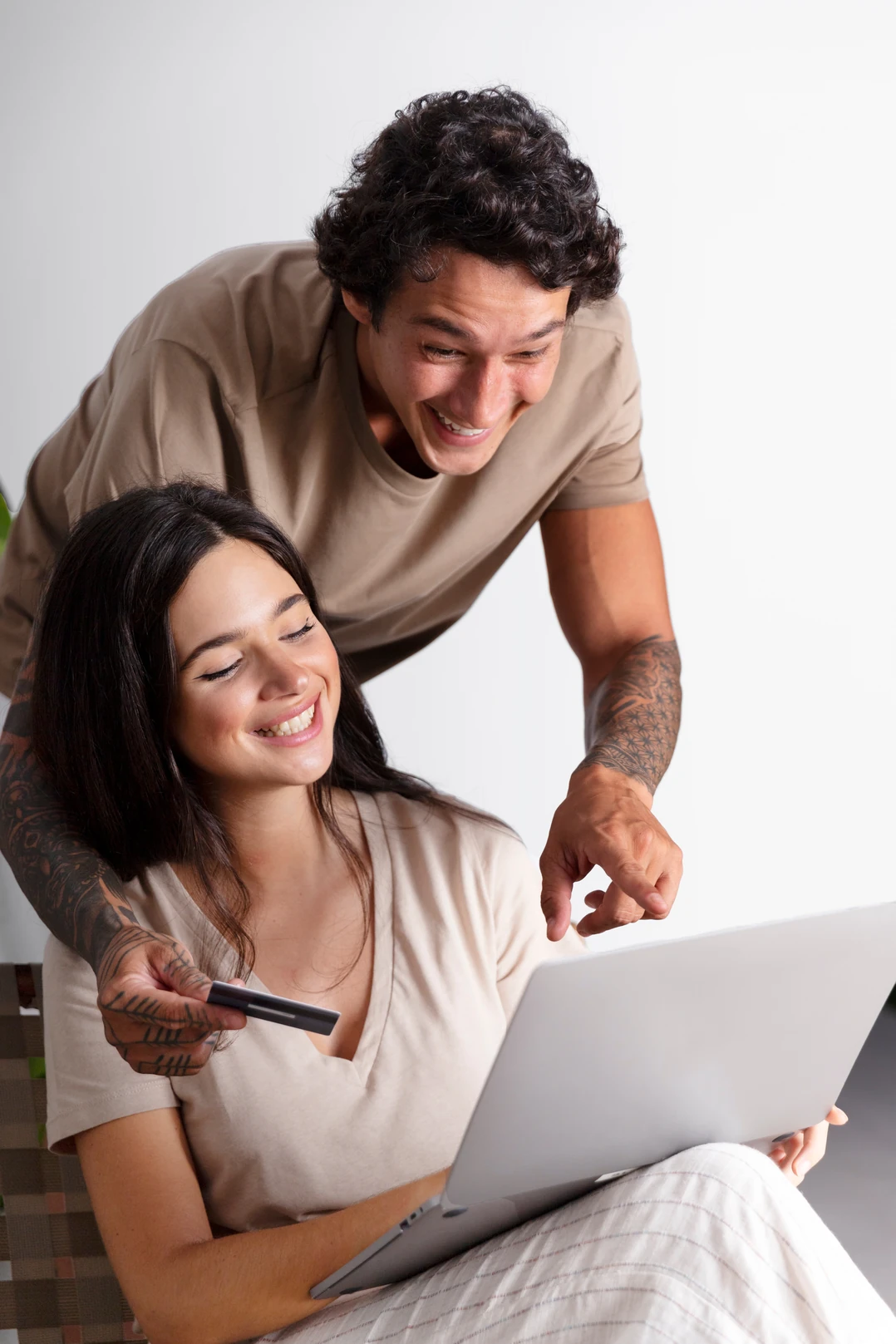 Smiling couple looking at a laptop together, one of them holding a bank card