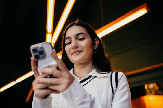 Young woman looking at her phone in a city at night